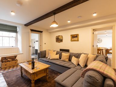 A living room with a gray sectional sofa and wooden coffee table next to a window at The Lodge in Newby Bridge