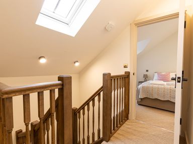 A wooden staircase with railing and a skylight leading to a bedroom with a bed at The Lodge in Newby Bridge