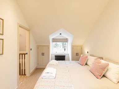 A bedroom with a bed towels windows and cupboards at The Lodge in Newby Bridge