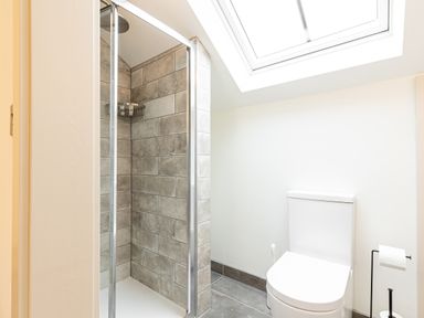 A bathroom with a glass shower enclosure and a white toilet under a skylight at The Lodge in Newby Bridge