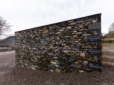A stone wall with signs for The Lodge and The Bothy at The Lodge in Newby Bridge