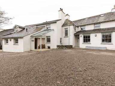 A gravel driveway leading to a white house with multiple windows and chimneys at The Lodge in Newby Bridge