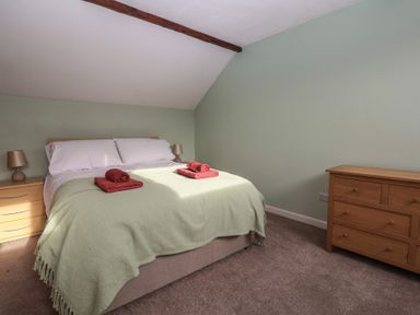 A bedroom with a bed, bedside tables with lamps and a wooden chest of drawers at Woodstock in Chaffcombe near Chard
