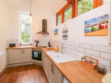 A kitchen with wooden countertops a white sink an oven a window and wall decorations at Baronet's Quarters in Lynton