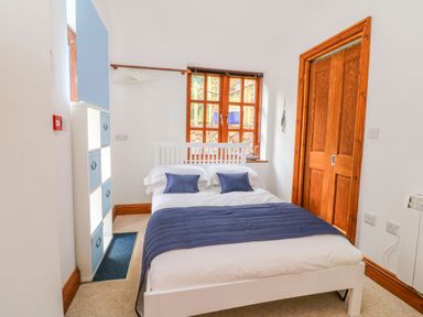 A bedroom with a white bed and blue pillows a wooden door and window at Baronet's Quarters in Lynton