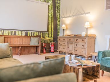 A living room with a wooden bench and green sofas by a wooden cabinet with lamps and a coffee table at Abbey Farm House in St Bees
