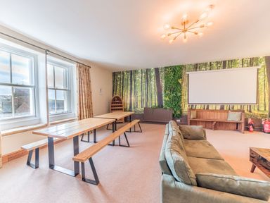 A room with wooden benches and table green sofa and a forest wallpaper at Abbey Farm House in St Bees