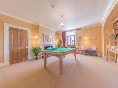 A game room with a pool table a wooden door a fireplace and a seating area at Abbey Farm House in St Bees