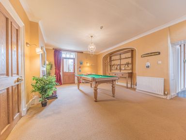 A game room with a billiard table a wooden door and a plant at Abbey Farm House in St Bees
