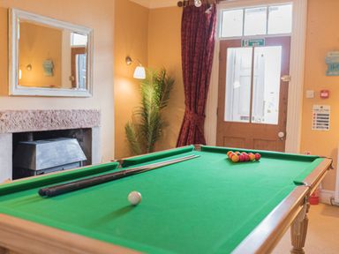 A room with a pool table with balls and cues near a door and a fireplace at Abbey Farm House in St Bees