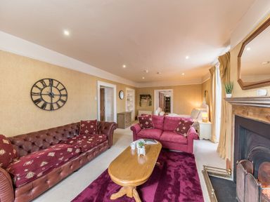 A living room with two sofas a wooden coffee table a fireplace and a bed at Abbey Farm House in St Bees