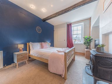A bedroom with a wooden bed and a blue accent wall at Abbey Farm House in St Bees