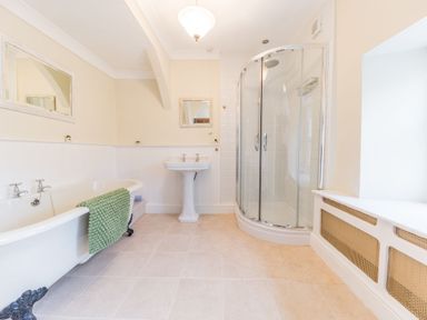 A bathroom with a clawfoot bathtub a pedestal sink a corner shower and a window seat at Abbey Farm House in St Bees