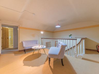 A seating area with two chairs and a round table next to a staircase at Abbey Farm House in St Bees