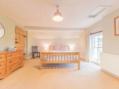 A bedroom with a wooden bed with cushions a dresser a wooden chair and a window at Abbey Farm House in St Bees