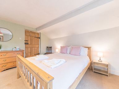 A bedroom with wooden double bed pillows bedside tables lamps and a wooden dresser at Abbey Farm House in St Bees