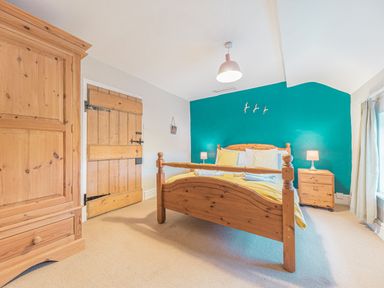 A bedroom with a wooden bed and furniture and a teal accent wall at Abbey Farm House in St Bees