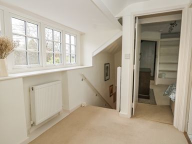 A hallway with a staircase and a window with multiple panes at Poppy Cottage in Beaminster