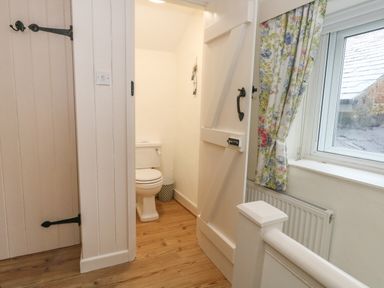 A small bathroom with a toilet and a wooden floor at Poppy Cottage in Beaminster