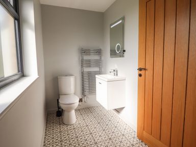 A bathroom with a toilet a sink with a mirror above a towel rack and a wooden door at Mynydd Y Glyn Lodge in Llanfyllin near Llanrhaeadr-Ym-Mochnant