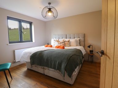 A bedroom with a bed with pillows and blankets near a window at Mynydd Y Glyn Lodge in Llanfyllin near Llanrhaeadr-Ym-Mochnant
