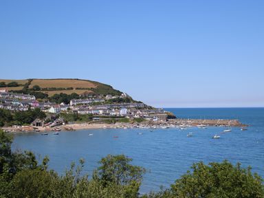 A coastal village with houses on a hill overlooking a bay with boats at Towyn Hall in New Quay