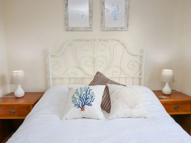 A bed with three decorative pillows and two bedside tables with lamps at Towyn Hall in New Quay