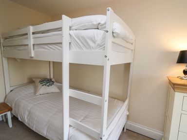 A bedroom with white bunk beds a side table and a lamp at Towyn Hall in New Quay