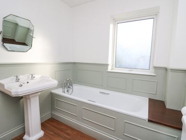 A bathroom with a pedestal sink a bathtub and a frosted window at Towyn Hall in New Quay
