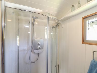 A bathroom with a corner shower enclosure and a window at Bosulla Shepherds Hut in Penzance