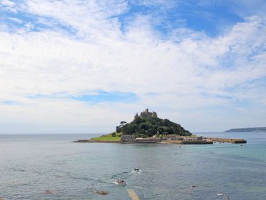 An island with a castle and buildings surrounded by water and boats in the sea