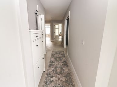 A hallway with a patterned runner rug and white cabinets at 19A Lighthouse Village in Fenit County Kerry