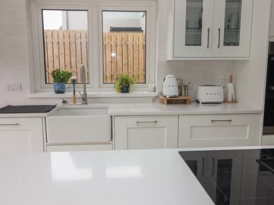 A kitchen counter with sink toaster kettle plants and cabinets at 19A Lighthouse Village Fenit County Kerry