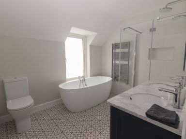 A bathroom with a toilet bathtub shower and double sink at 19A Lighthouse Village in Fenit County Kerry