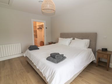 A bedroom with a bed with white linens and gray towels two wooden nightstands and an open door to a closet at 19A Lighthouse Village in Fenit County Kerry