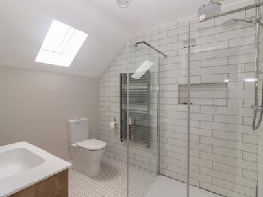 A bathroom with a toilet a sink a glass shower enclosure and a skylight at 19A Lighthouse Village in Fenit County Kerry