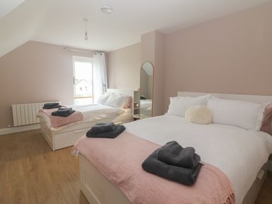 A bedroom with two beds each with folded towels a standing mirror and a window at 19A Lighthouse Village in Fenit County Kerry