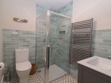 A bathroom with a shower cubicle a toilet a towel radiator and a sink at 19A Lighthouse Village in Fenit County Kerry