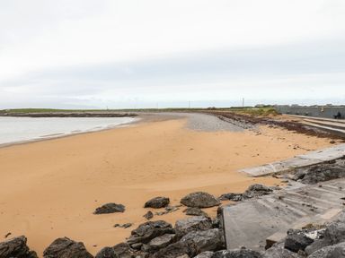 A sandy beach with rocks and a concrete ramp near a promenade at 19A Lighthouse Village in Fenit County Kerry