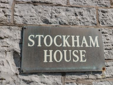 A metal sign reading stockham house mounted on a textured stone wall at 49 Esplanade in Burnham-On-Sea
