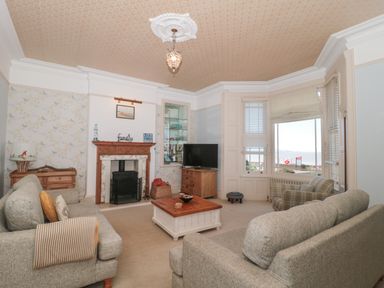 A living room with two sofas a wooden coffee table fireplace and a television at 49 Esplanade in Burnham-On-Sea