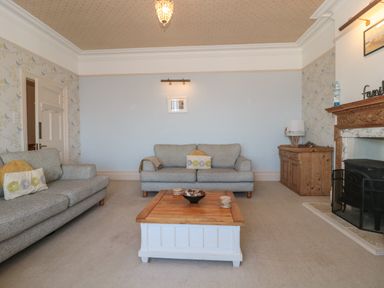 A living room with two sofas a wooden coffee table a wooden cabinet and a fireplace at 49 Esplanade in Burnham-On-Sea