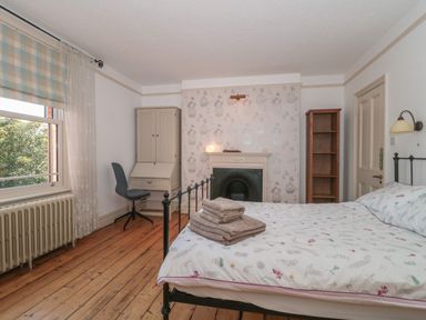 A bedroom with a bed a stack of towels a desk chair a cabinet a fireplace and a window at 49 Esplanade Burnham-On-Sea