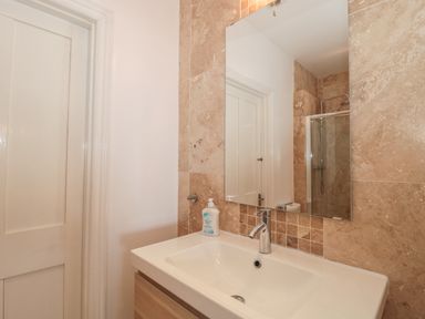 A bathroom sink with a mirror above and a door to the left at 49 Esplanade in Burnham-On-Sea