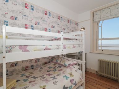 A bedroom with bunk beds and a window showing a sea view at 49 Esplanade in Burnham-On-Sea