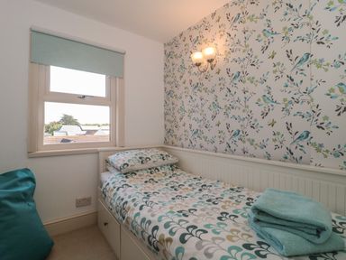 A bedroom with a single bed and floral wallpaper at 49 Esplanade in Burnham-On-Sea