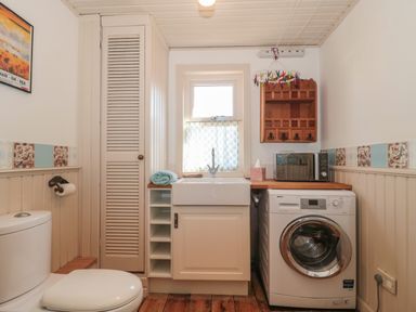 A laundry room with a toilet sink washing machine and microwave at 49 Esplanade Burnham-On-Sea