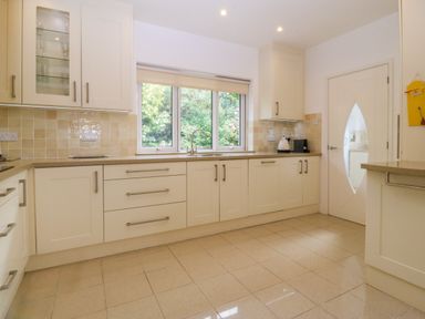 A kitchen with cabinets drawers a window with a blind a sink a kettle and a microwave at Gwylanod in Llwyngwril near Fairbourne