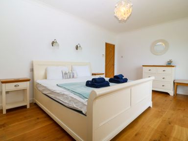 A bedroom with a bed with blue towels on it a dresser and two bedside tables at Gwylanod in Llwyngwril near Fairbourne