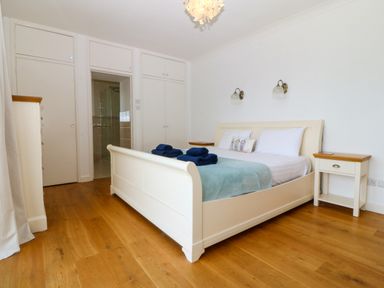 A bedroom with a bed two bedside tables and wooden floor at Gwylanod in Llwyngwril near Fairbourne